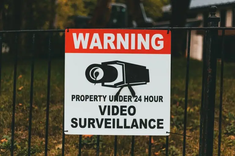 Video surveillance warning sign on metal fence outdoors.